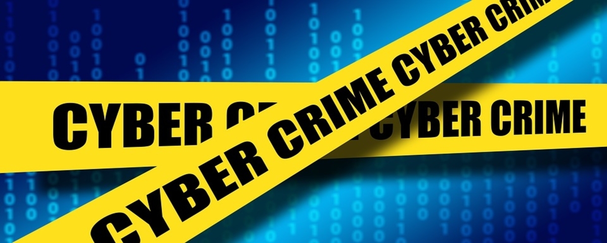Yellow police tape that says "Cyber Crime" wrapped in front of a blue digital screen.