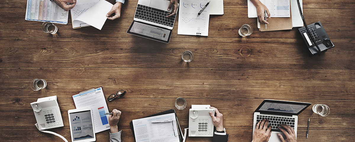 Office employees reviewing productivity reports on paper and laptop computers.