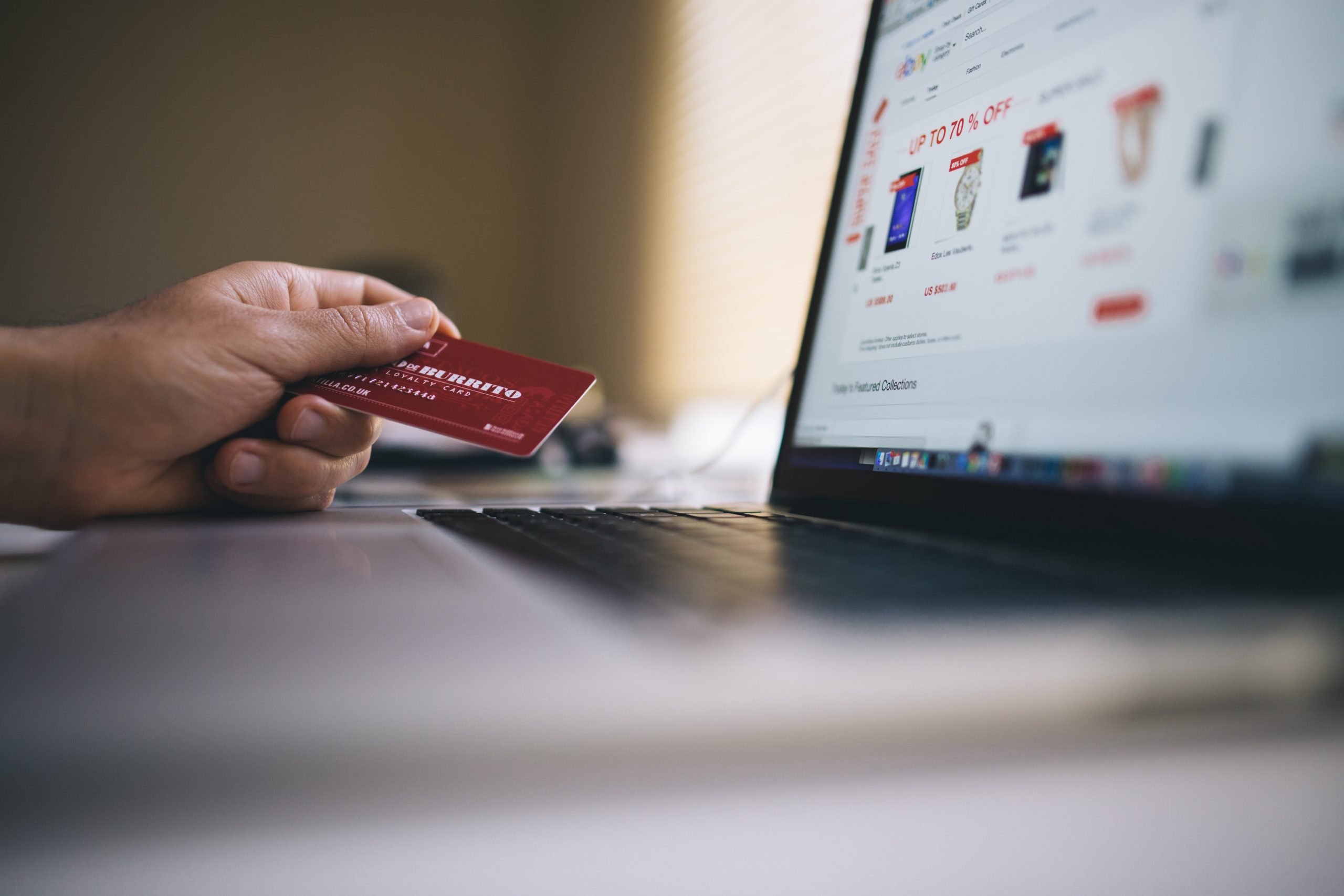 A person holds their credit card in their hand while they shop online. Context: the VPNFilter malware can collect payment data from infected networks