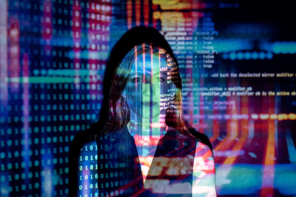 A picture of a woman. Colorful computer code is projected on top of her and in the background