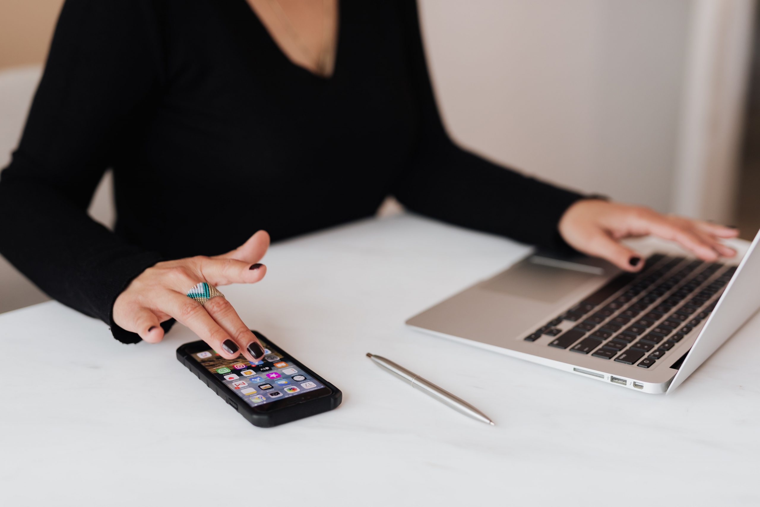 A woman uses her phone and laptop simultaneously