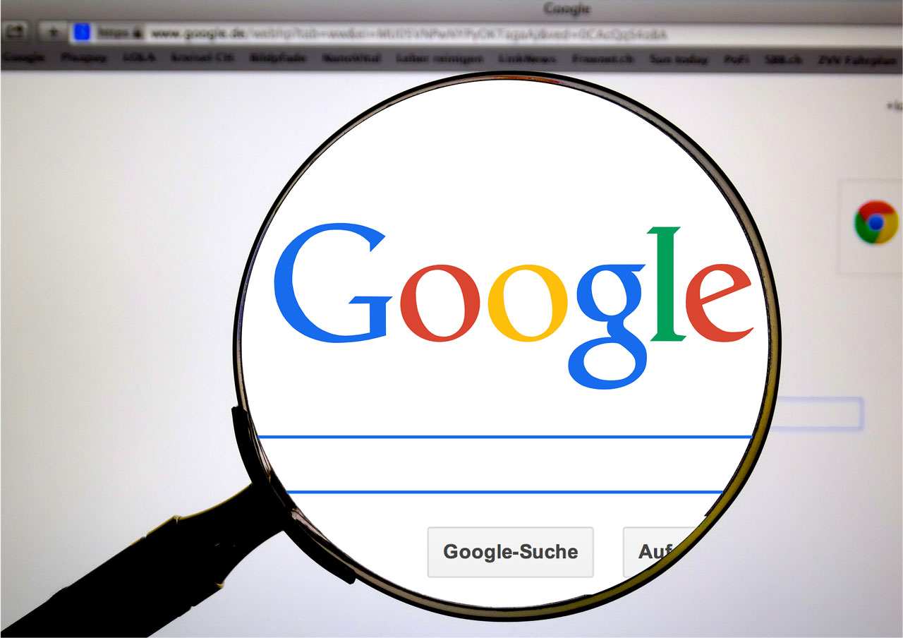 A computer screen with the Google.com homepage. There is a magnifying glass enlarging the Google logo.