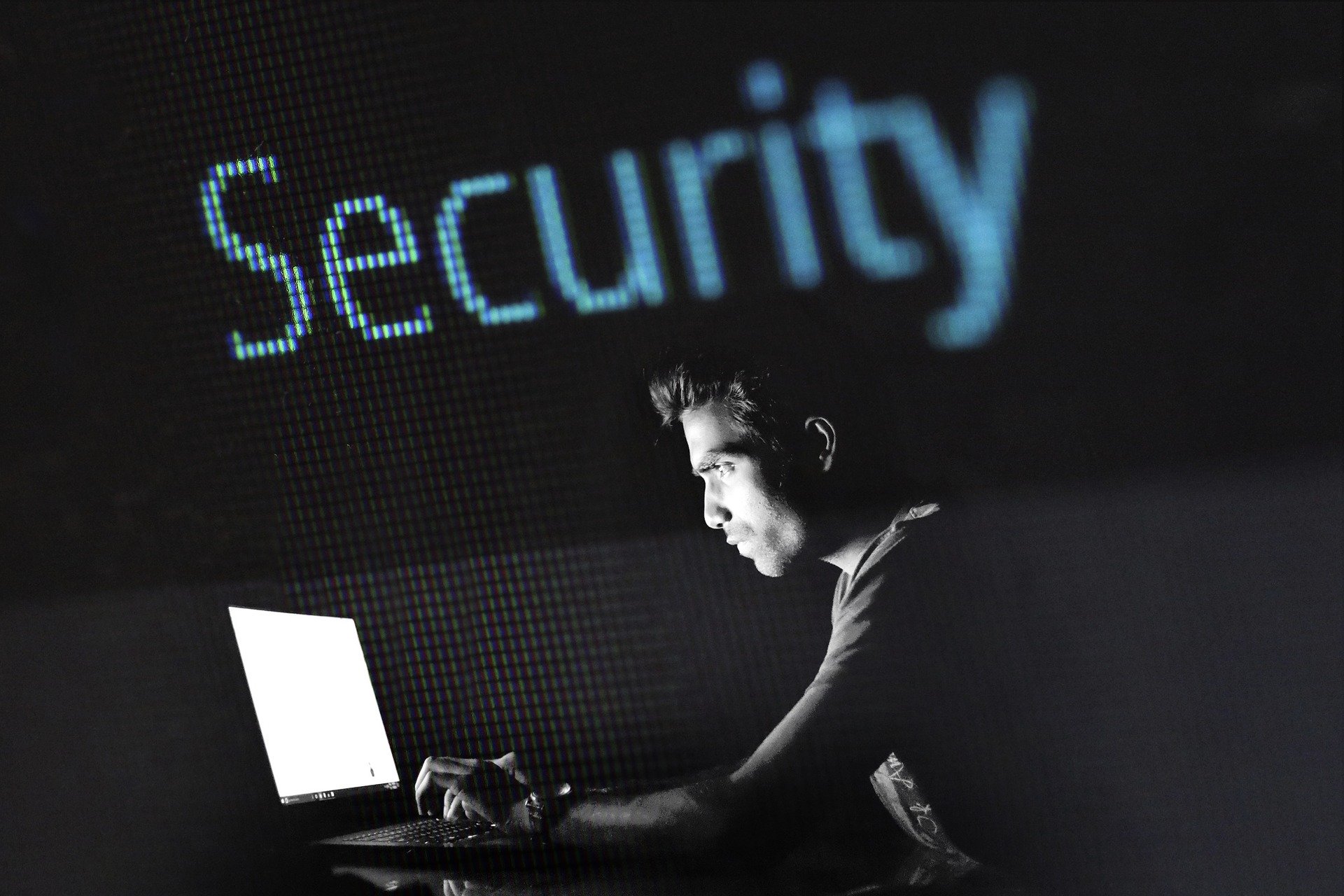 A greyscale man in a dark room looks at his laptop screen. A header above him says "security"