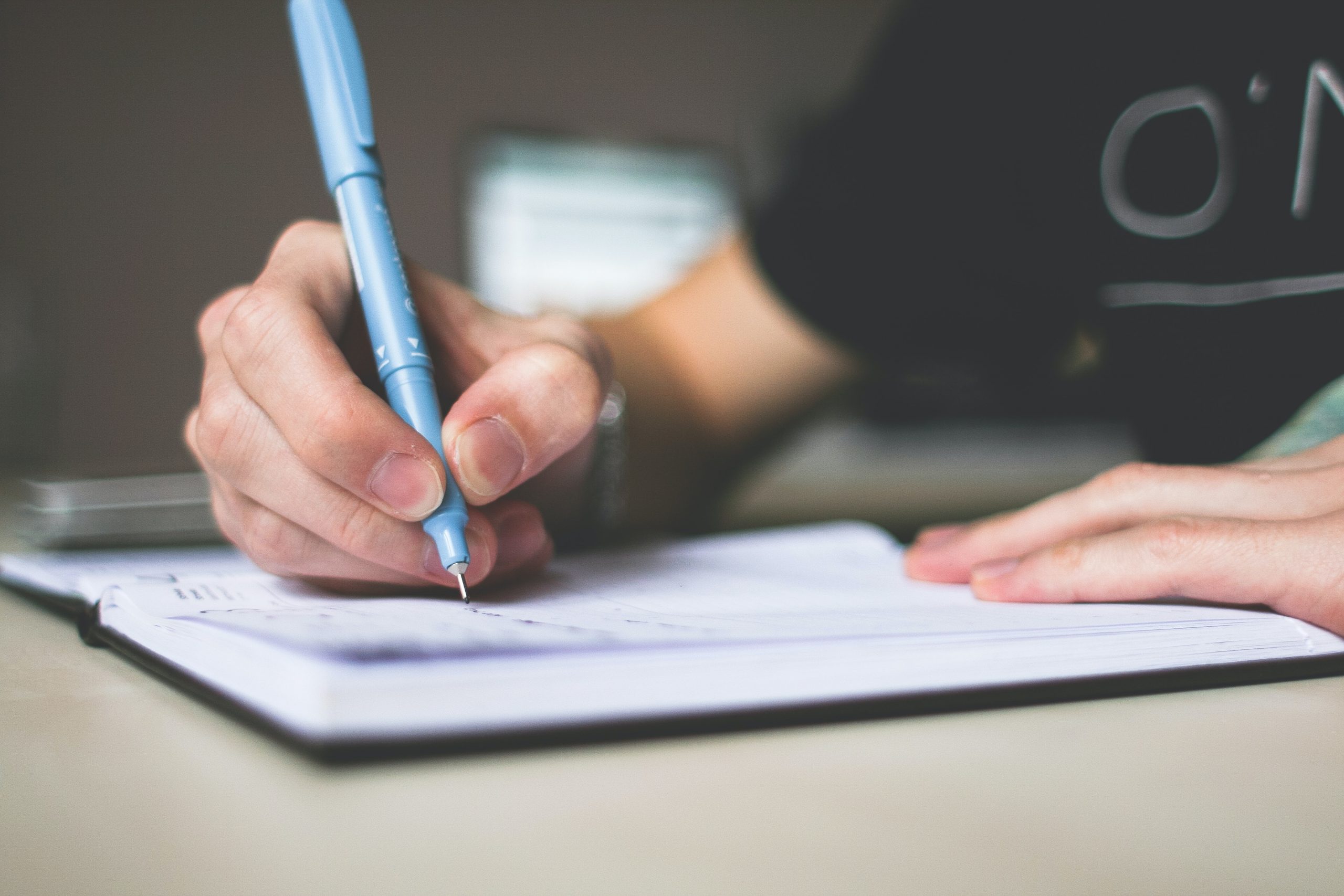 A man uses a pen to write notes in a notebook