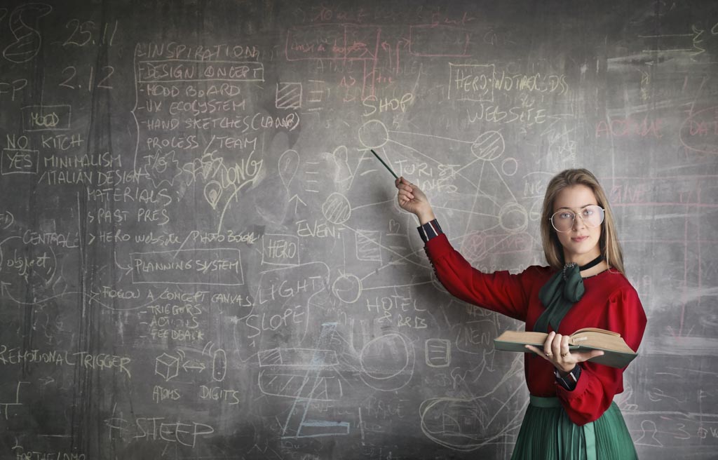 A female teacher points to a chalkboard