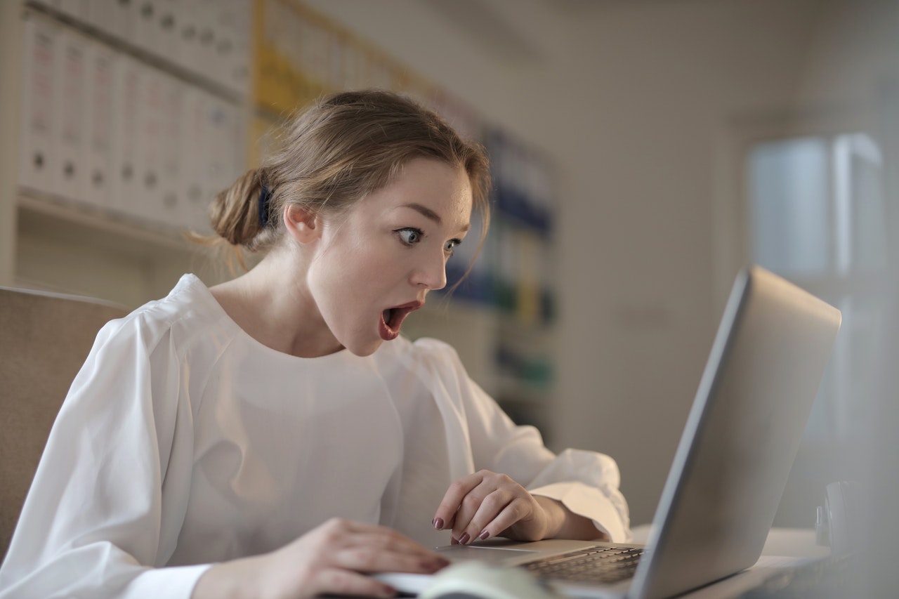 A shocked woman stares at her computer screen