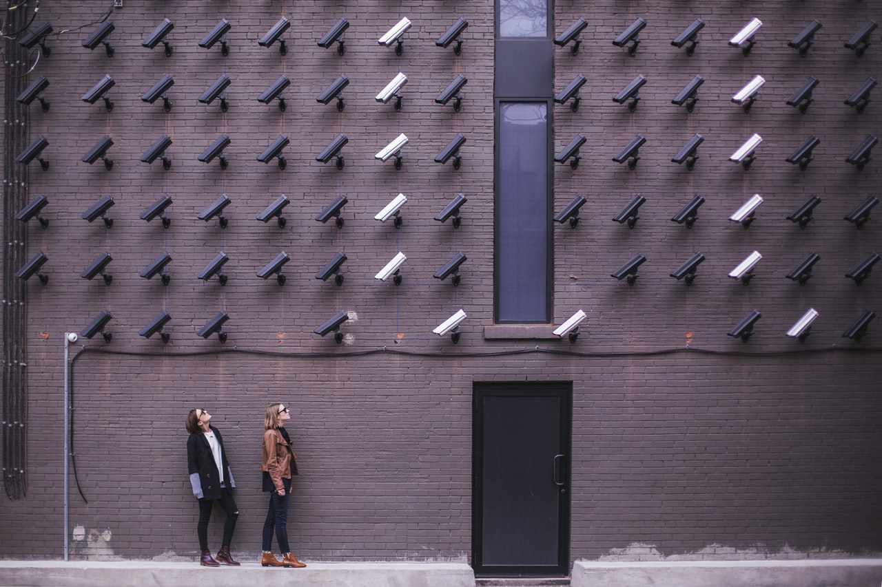 A wall of multiple security cameras pointed at two people