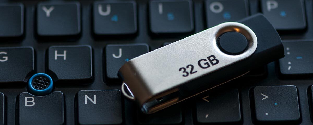 A 32 gigabyte USB flash drive sitting on top of a computer keyboard