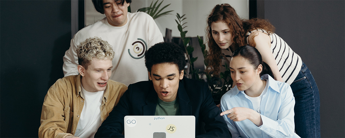A group of employees surround a laptop. They all have worried expressions