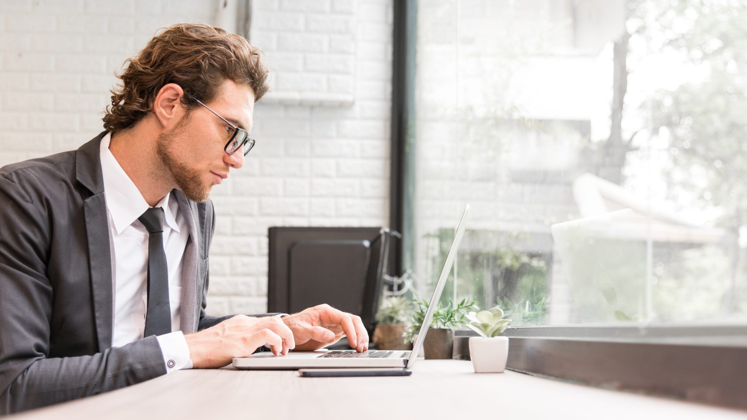 young employee in a business suit working on a laptop