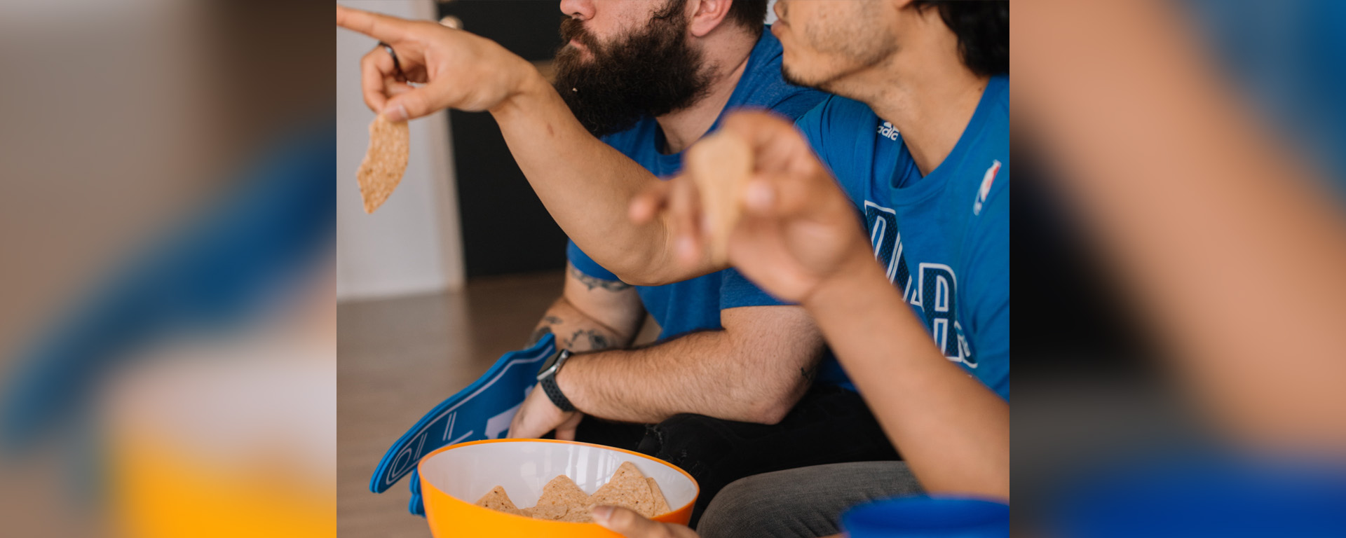 Two men in sports jerseys watching March Madness basketball