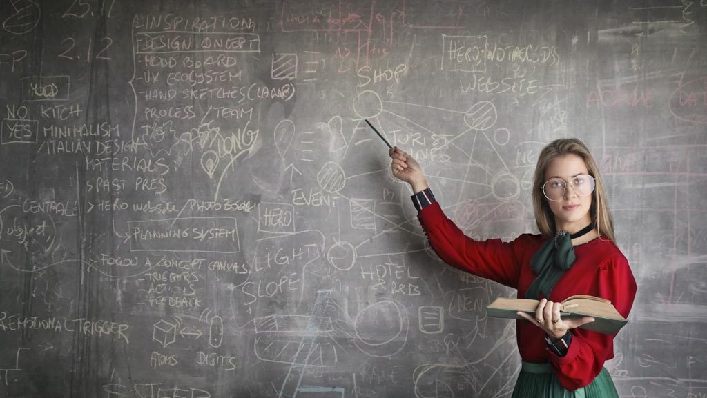 A female teacher points to a chalkboard