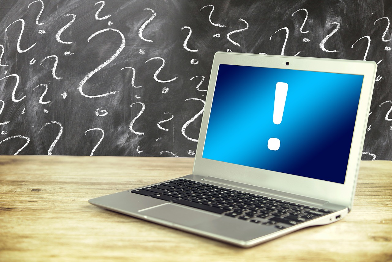 Background: Chalkboard with question marks. Foreground: Laptop computer with an exclamation mark on the screen